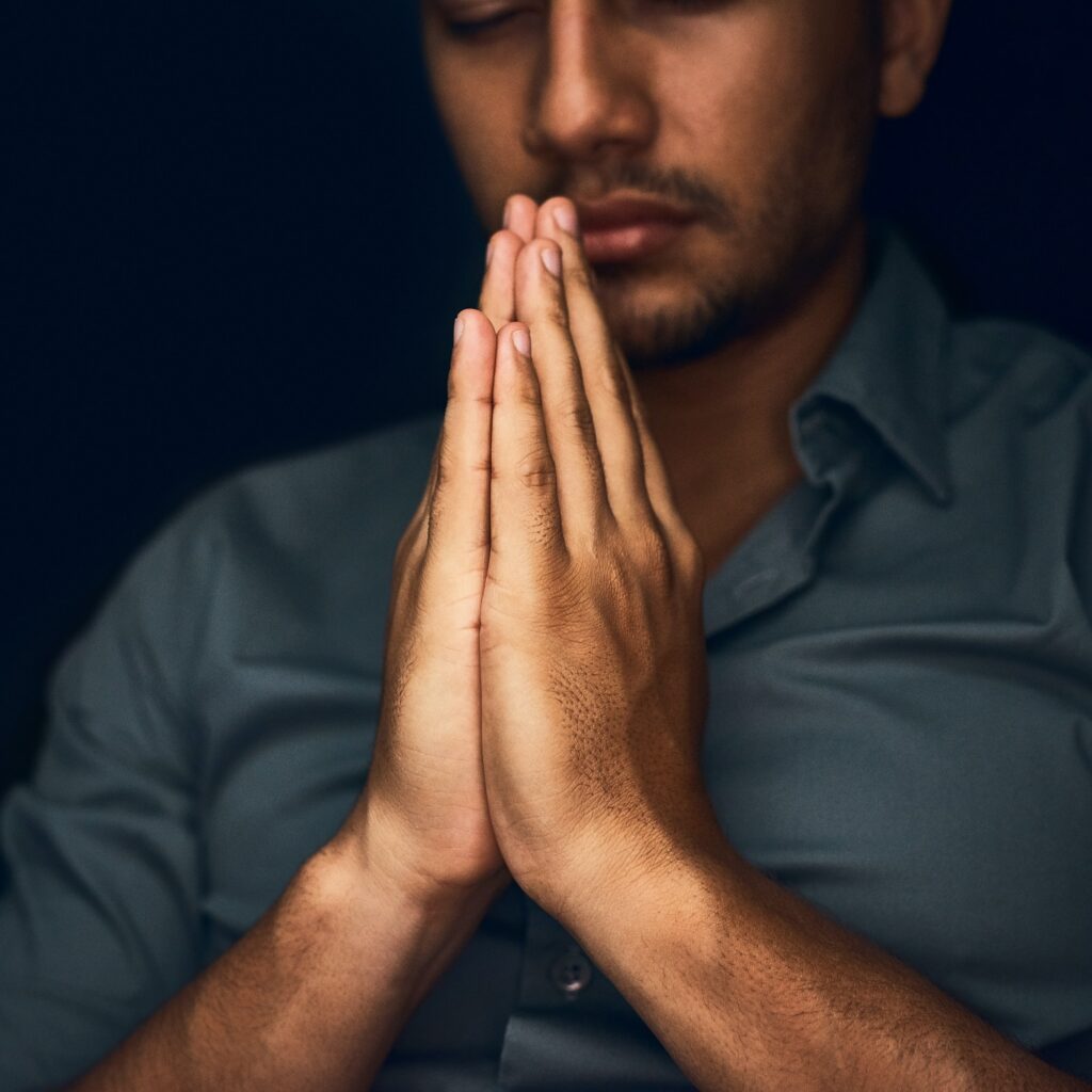 give us this day our daily bread closeup shot of a young man praying with his eyes closed .jpg