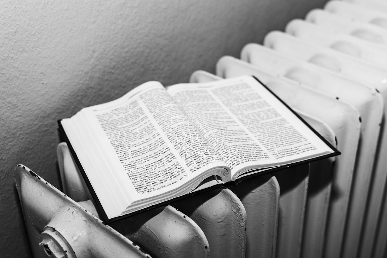 Home Open Bible on a radiator in black and white, symbolizing warmth and knowledge.